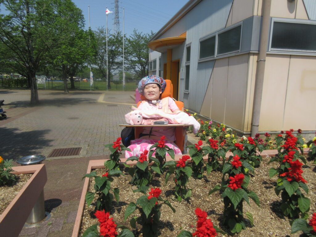 みすぎ 赤い花の前で笑顔の利用者様