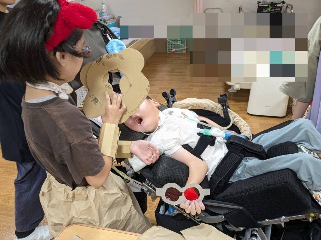 さん　段ボールでできた飾りで変身あそびをする利用者様